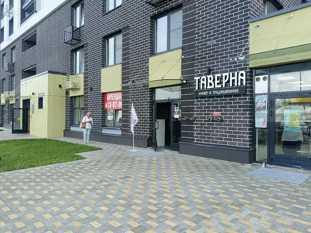 Фасад дома на Родионова, 31 с вывеской «Таверна» под жёлто-оливковой маркизой